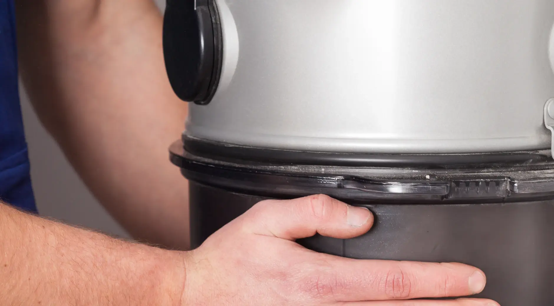 Technician removing the waste bin from a central vacuum power unit for emptying